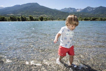 Baby boy walking alone on lakeshore, Embrun, Provence-Alpes-Cotes d'Azur, France - AURF05973
