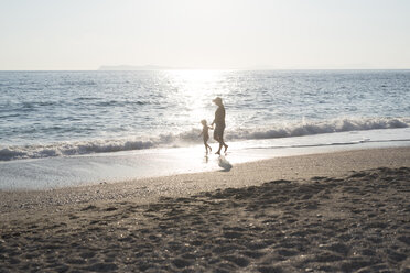 Griechenland, Parga, Mutter und Tochter spazieren am Strand bei Sonnenuntergang - PSIF00101