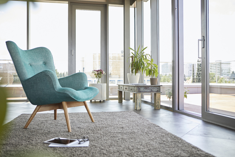 Hausinterieur mit Sessel, Tablet und Blick auf die Dachterrasse, lizenzfreies Stockfoto