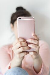 Woman's hands holding pink smartphone, close-up - FLMF00061