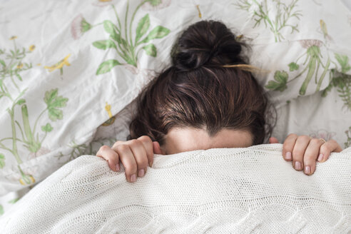 Frau liegt im Bett und bedeckt ihr Gesicht mit einer Decke - FLMF00062