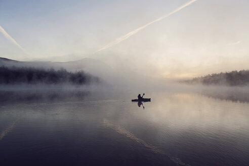 Junge Frau paddelt am frühen Morgen im Kajak durch den Nebel auf dem Daicey Pond im Baxter State Park in Maine, USA - AURF06114