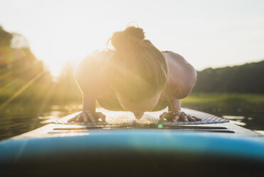 Young woman doing SUP yoga at golden hour, North Kingstown, Rhode Island, USA - AURF06117