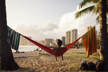 Young woman sitting in hammock at beach, Honolulu, Hawaii Islands, USA - AURF06120