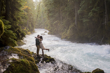 Couple kissing on riverbank at McKenzie River near Sahalie Falls, Oregon, USA - AURF06179