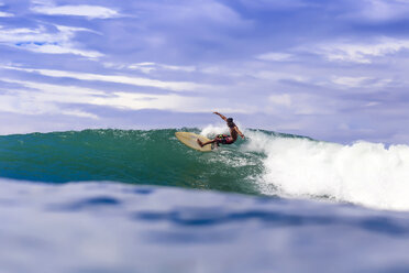 Clouds over male surfer riding wave, Kuta, Lombok, Indonesia - AURF06184