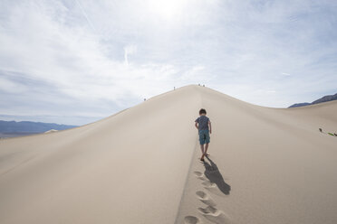 Wolken über einem Jungen, der auf den Mesquite Flat Sanddünen im Death Valley National Park, Kalifornien, USA, spazieren geht - AURF06186