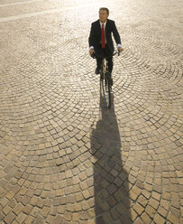 Erhöhte Ansicht eines Geschäftsmannes, der mit dem Fahrrad über die Piazza fährt - AURF06227