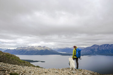 Female hiker with dog on Monarch Mountain overlooking Atlin Lake, Canada - AURF06244