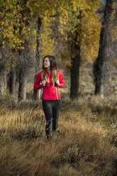 Wanderin, die im Herbst durch hohes Gras wandert, Wyoming, USA - AURF06256