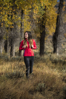Wanderin, die im Herbst durch hohes Gras wandert, Wyoming, USA - AURF06256