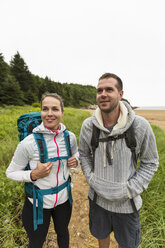 Front view of couple hiking on cloudy morning at Sand Beach in Acadia National Park, Maine, USA - AURF06319