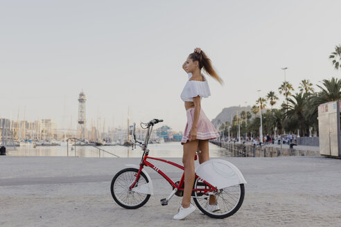 Fashionable young woman exploring Barcelona with a bicycle - AFVF01594