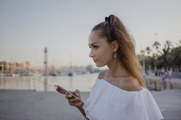 Junge Frau mit Smartphone am Hafen von Barcelona, Porträt - AFVF01601