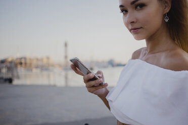 Junge Frau mit Smartphone am Hafen von Barcelona, Porträt - AFVF01602