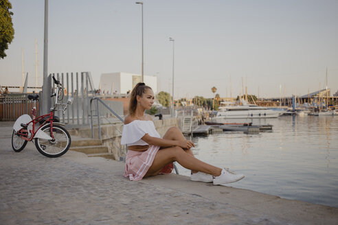 Modische junge Frau, die am Hafen von Barcelona, Spanien, sitzt - AFVF01604