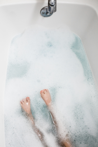 Niedriger Ausschnitt eines Jungen mit Schaumbad in der Badewanne, lizenzfreies Stockfoto