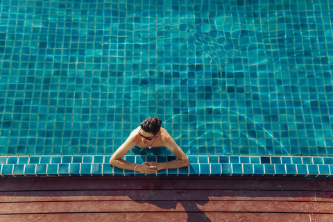 Hoher Blickwinkel auf einen Mann ohne Hemd, der sich im Schwimmbad eines Ferienortes entspannt, lizenzfreies Stockfoto