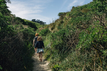 Rear view of siblings walking amidst plants - CAVF48807