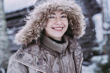 Close-up portrait of happy woman standing outdoors during snowfall - CAVF48824