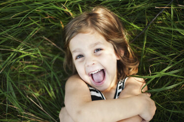 High angle portrait of happy girl lying on grassy field at park - CAVF48826