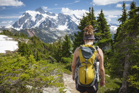 Rear view of female hiker with backpack walking at North Cascades National Park stock photo