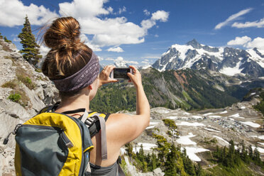 Rear view of hiker photographing with mobile phone on mountain at North Cascades National Park - CAVF48877