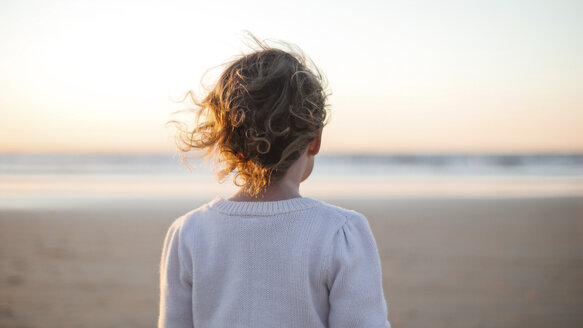 Rückansicht eines am Strand stehenden Mädchens gegen den Himmel bei Sonnenuntergang - CAVF48936