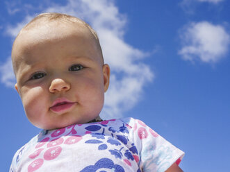 Low angle portrait of cute baby girl standing against blue sky during sunny day - CAVF48940