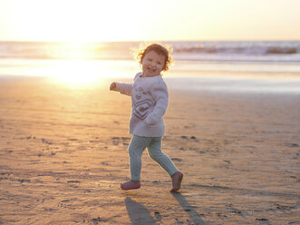 Happy Baby Mädchen läuft am Strand gegen klaren Himmel bei Sonnenuntergang - CAVF48945