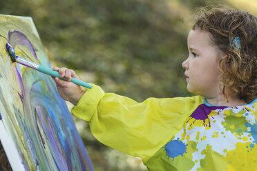 Süßes Baby Mädchen malen auf Leinwand im Hof - CAVF48946