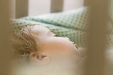 Nahaufnahme von niedlichen Baby-Mädchen schlafen in Krippe durch Geländer zu Hause gesehen - CAVF48953