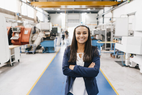 Confident woman working in high tech enterprise, standing in factory workshop with arms crossed - KNSF04800