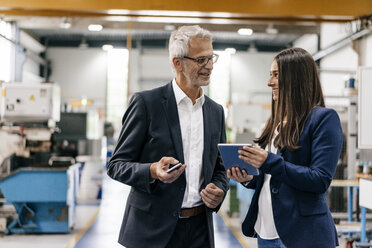 Ein Geschäftsmann und eine Frau in einem High-Tech-Unternehmen treffen sich in einer Fabrikhalle - KNSF04832