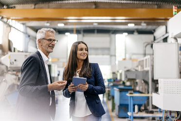 Businessman an woman in high tech enterprise, having a meeting in factory workshop - KNSF04833