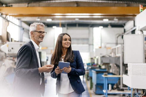 Ein Geschäftsmann und eine Frau in einem High-Tech-Unternehmen treffen sich in einer Fabrikhalle - KNSF04833