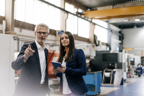 Ein Geschäftsmann und eine Frau in einem High-Tech-Unternehmen treffen sich in einer Fabrikhalle - KNSF04834