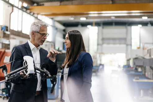 Businessman an woman in high tech enterprise, discussing production of drones - KNSF04835