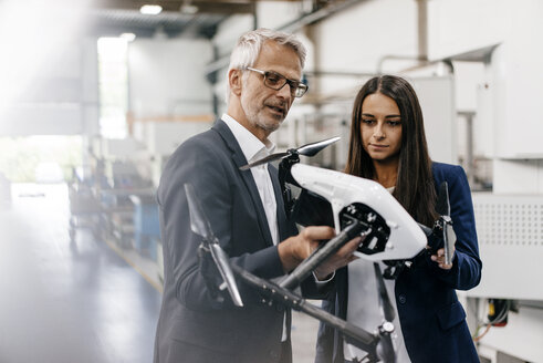 Businessman an woman in high tech enterprise, discussing production of drones - KNSF04836