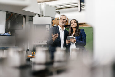 Ein Geschäftsmann und eine Frau in einem High-Tech-Unternehmen treffen sich in einer Fabrikhalle - KNSF04841