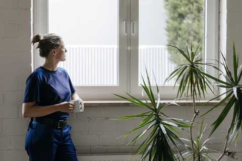 Junge Frau, die in einem High-Tech-Unternehmen arbeitet, macht eine Pause und trinkt Kaffee, lizenzfreies Stockfoto