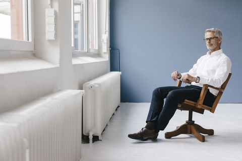 Ein Manager sitzt in seinem Büro, schaut aus dem Fenster und denkt nach, lizenzfreies Stockfoto