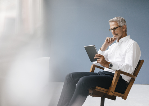 Manager im Büro sitzend, mit digitalem Tablet, lizenzfreies Stockfoto