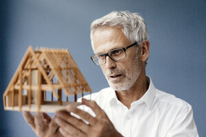 Ein erfolgreicher Architekt betrachtet das Modell eines Hauses - KNSF04872