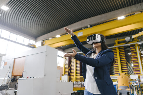Young woman working in distribution warehouse, wearing VR glasses - KNSF04885