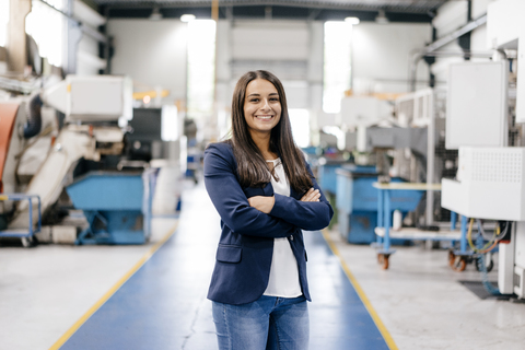 Confident woman working in high tech enterprise, standing in factory workshop with arms crossed stock photo