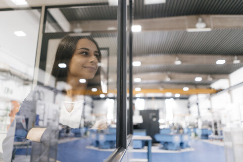 Confident woman working in high tech enterprise, looking out of control room - KNSF04902