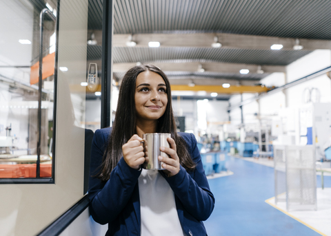 Selbstbewusste Frau, die in einem Hightech-Unternehmen arbeitet und Kaffee trinkt, lizenzfreies Stockfoto