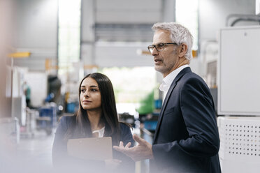 Businessman an woman in high tech enterprise, having a meeting in factory workshop - KNSF04907