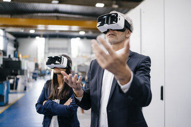 Businessman an woman in high tech enterprise, using VR glasses - KNSF04908